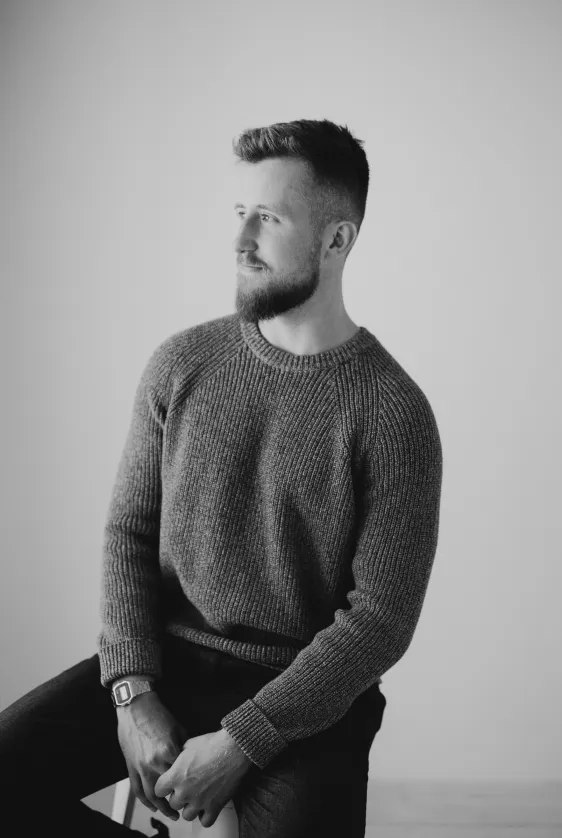 A black and white portait of me sat on a chair, looking to the right—there's a faint hint that I might be thinking about something profound, but unfortunately, I can assure you that I was not.